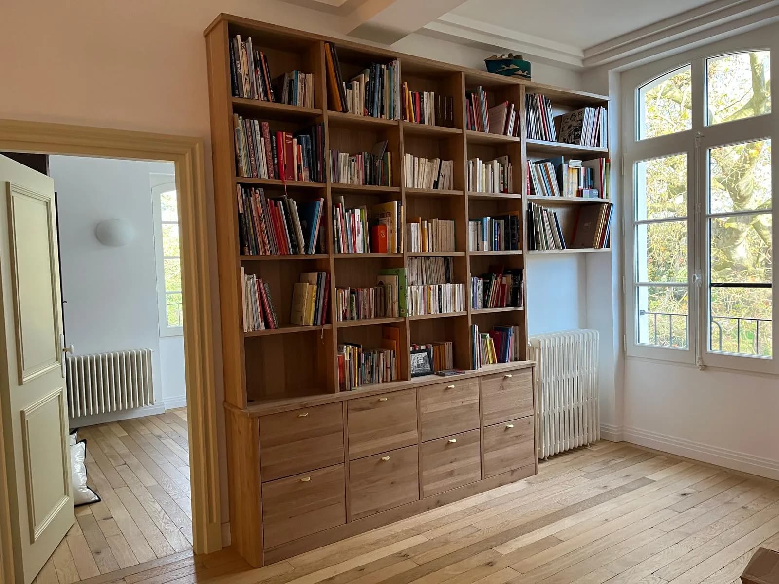 Bibliothèque en chêne à cases ouvertes remplies de livres, avec rangée de grands tiroirs en partie basse
