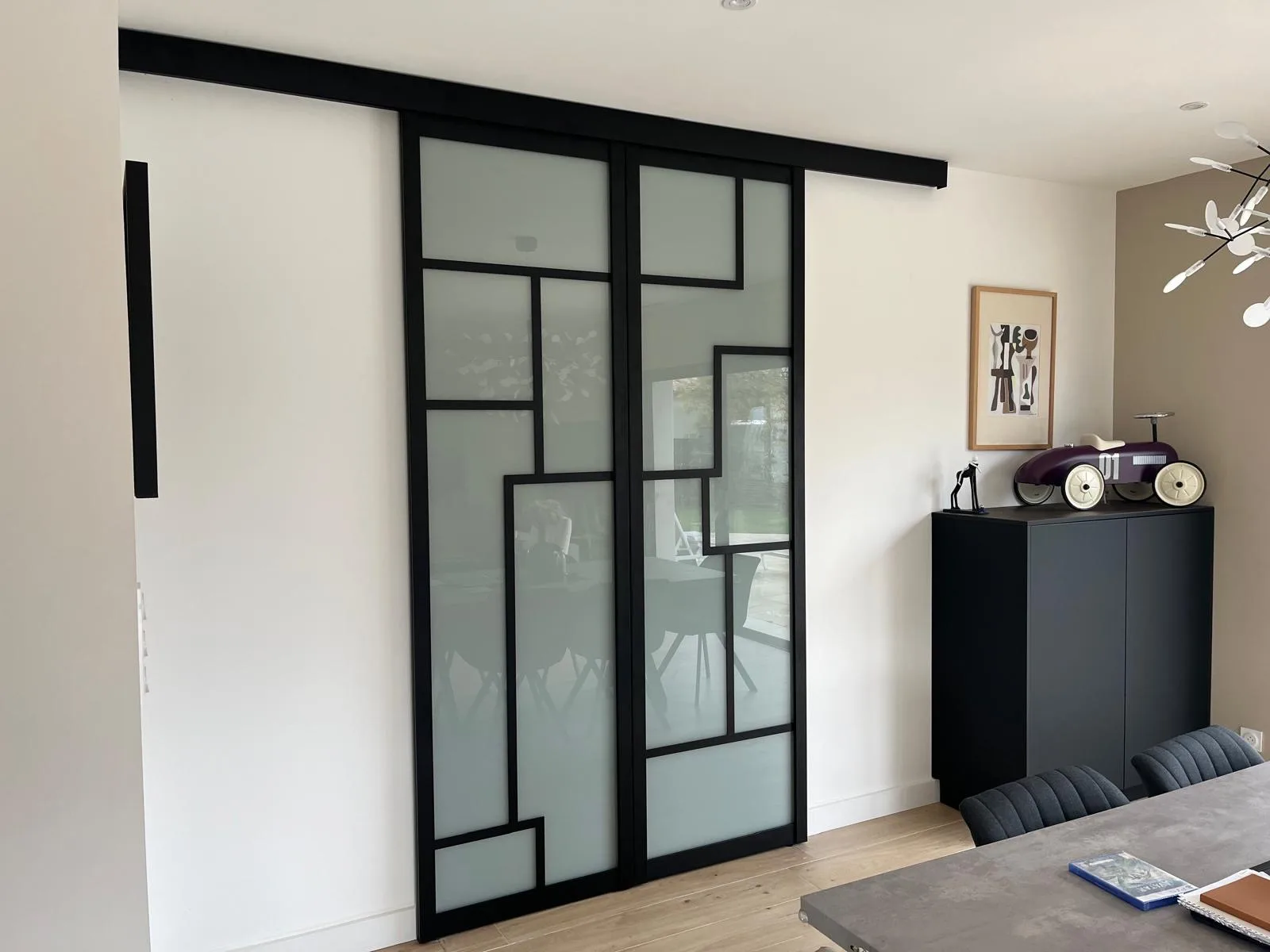Portes coulissantes suspendues à cadre noir type verrière et panneaux en verre dépoli à croisillons