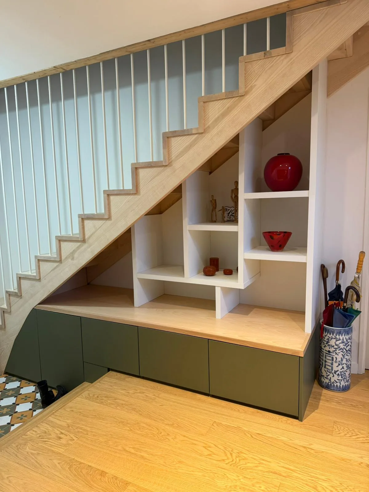 Aménagement sous escalier avec caissons bas vert kaki, niches ouvertes blanches et plateau en chêne clair